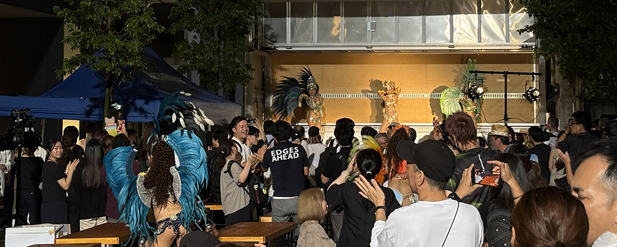 2026年7月24日夜開催の夏祭り「岩三サマーフェスティバル2026」の様子です。開催直前まで降り続いた雨も上がり、会場はサンバカーニバルで大盛り上がりです。美しいサンバダンサーのみなさんが特設ステージ、そして会場内でサンバしまくっています。踊りまくっています。主催者の岩本町三丁目町会は晴れ男晴れ女の集まりかもしれません。開催時間直前までの悪天候、ゲリラ雷雨も、土砂降りもピタッと止めて無事開催。そんな運、持ってます。