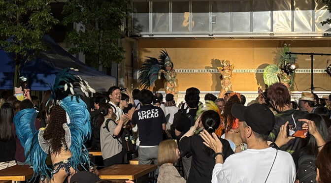 岩本町三丁目町会の公式ホームページの投稿「ゲリラ雷雨もカラッと晴れて。岩三サマーフェスティバル2026、ご来場ありがとうございました。（7月24日）」のアイキャッチ画像です。超盛り上げ裏のサマフェス会場。サンバダンサー、ご来場いただいたみなさま、踊っています。