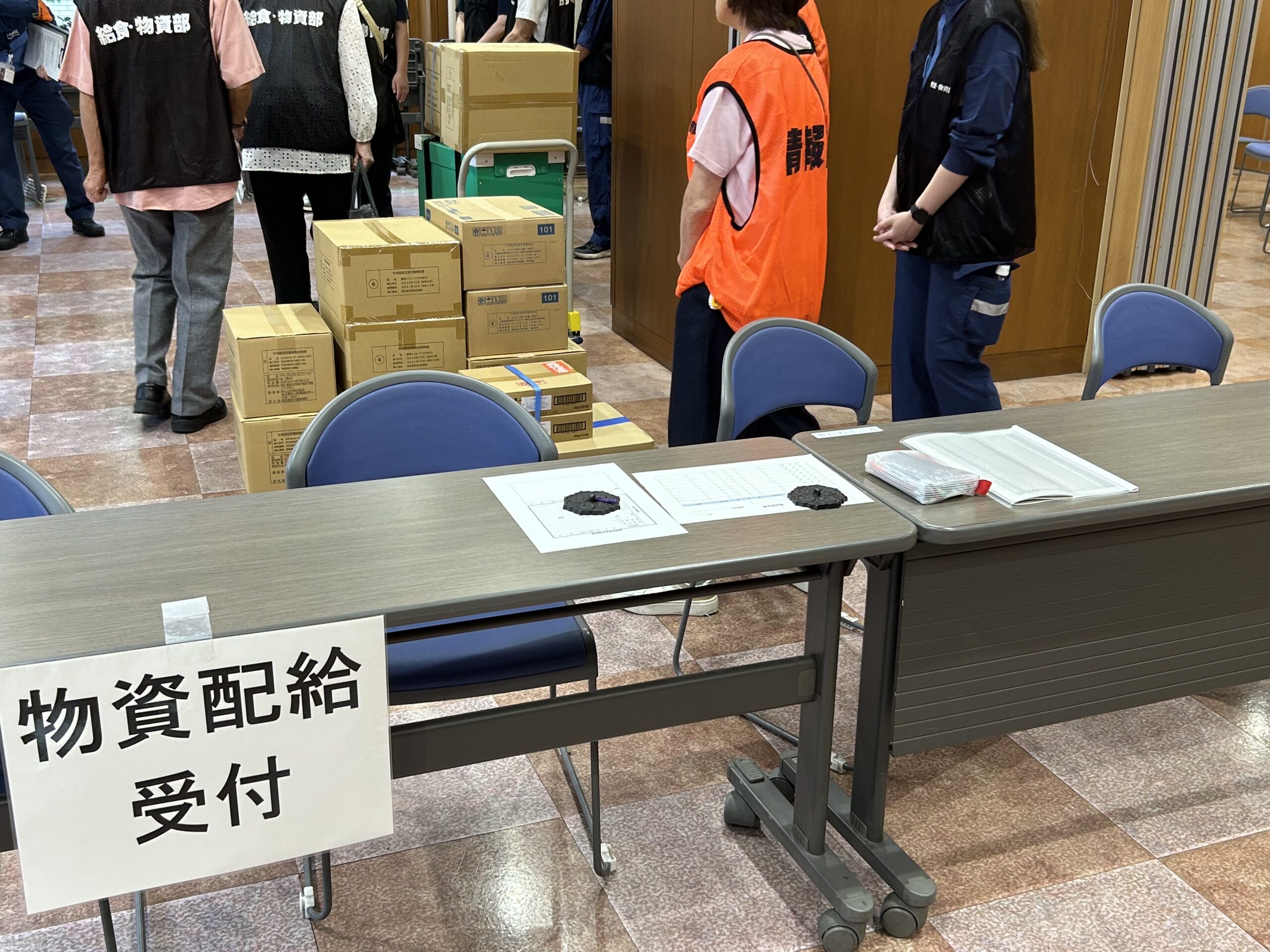 災害時に神田岩本町そして岩本町三丁目等の住民のために開設される「岩本町ほほえみプラザ」避難所の開設訓練で設置した物資供給用の受付の写真です。ここで飲料水等を配布します。
