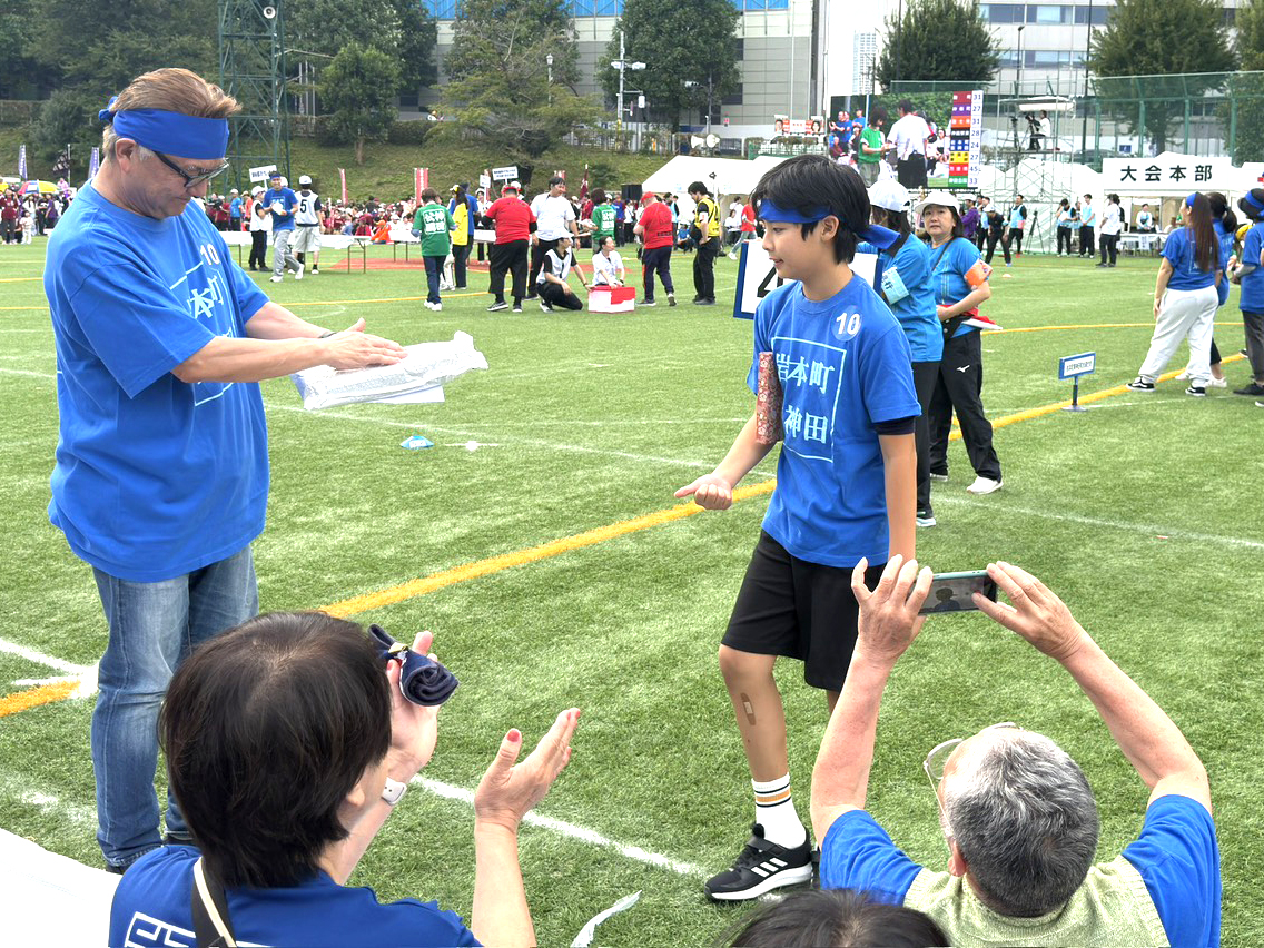 「任務完了」「よくやった」。第64回千代田区民体育大会の買い物競争に参加した岩本町三丁目町会の10代男子。町会の皆さんから拍手で迎えられています。